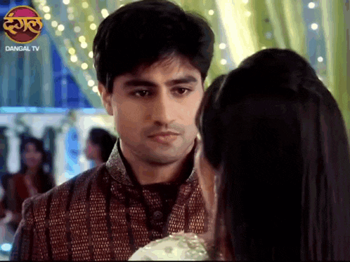 a man and a woman are looking at each other with a dangal tv logo in the background