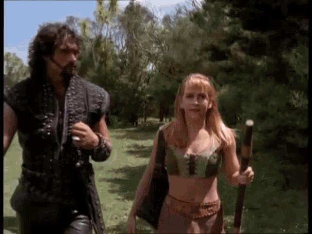 a man and a woman are walking through a field .