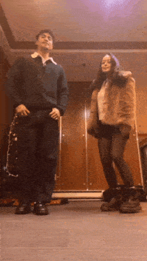 a man and a woman are standing next to each other in a room