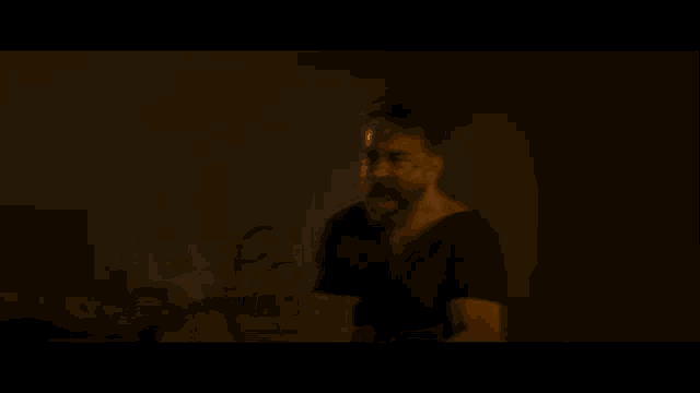 a man is standing in front of a fire in the dark