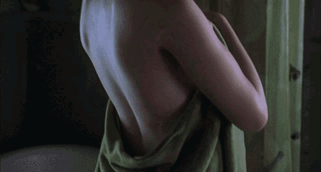 a woman wrapped in a green towel is standing in a bathroom