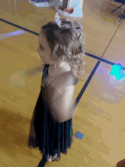 a little girl with a tiara on her head is standing on a wooden floor