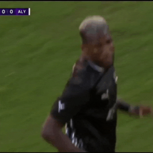 a soccer player wearing a black puma jersey is running on a field
