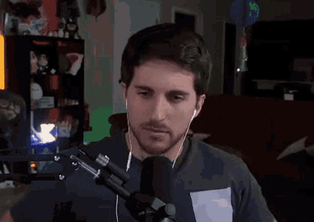 a man wearing headphones is sitting in front of a microphone in a room .