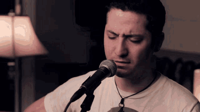 a man singing into a microphone wearing a white shirt