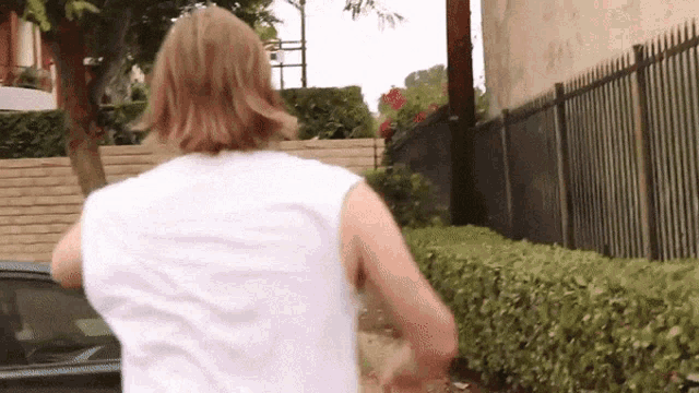 a woman in a white tank top is running down a street