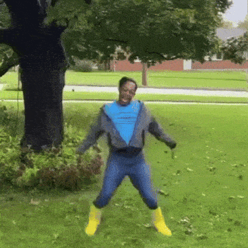 a man wearing a blue shirt and yellow boots is jumping in the grass