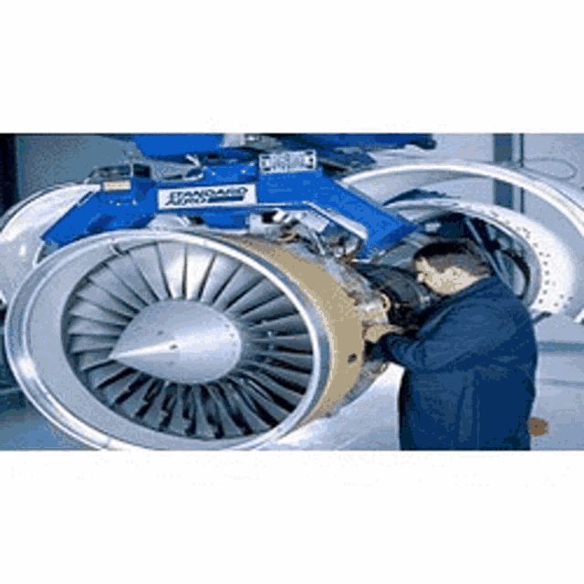 a man is working on a large jet engine in a factory .