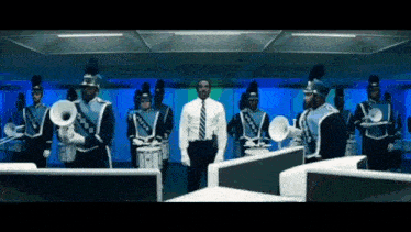 a man stands in front of a marching band playing drums