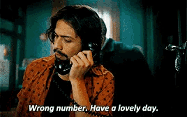 a man is talking on a phone and saying `` wrong number , have a lovely day . ''