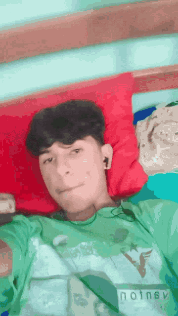 a young man wearing a green shirt that says noisy is laying on a bed