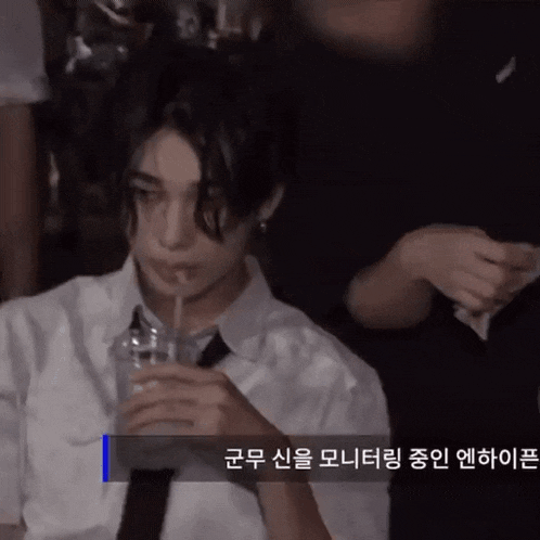 a man in a white shirt and tie is drinking from a plastic cup with a straw ..