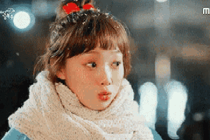a young girl wearing a scarf and a bow in her hair .