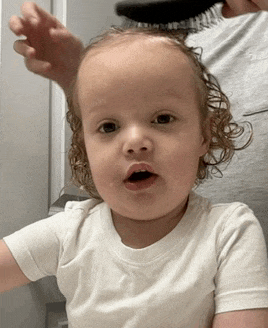 a person is brushing a toddler 's hair with a brush