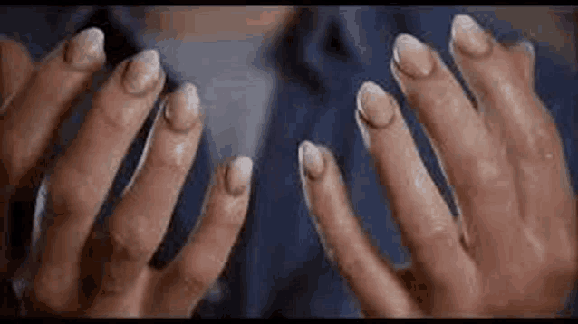 a close up of a person 's hands with long nails and a blue shirt .