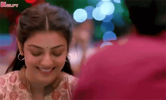 a woman is smiling while looking at a man 's face .