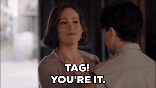 a man and a woman are looking at each other and the woman is saying tag you 're it