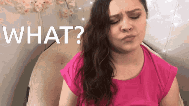 a woman in a pink shirt has her eyes closed and the words what behind her