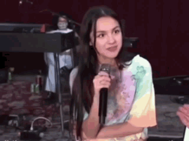 a young woman is holding a microphone on a stage and talking into it .