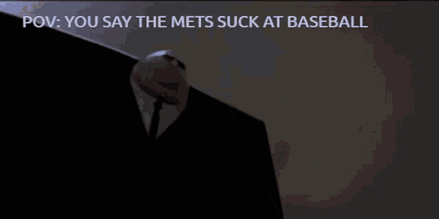 a man in a suit is holding a baseball and says " you say the mets suck at baseball " on the bottom