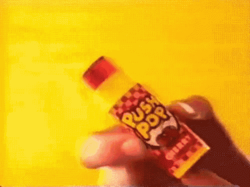 a person is holding a bottle of push pop candy .