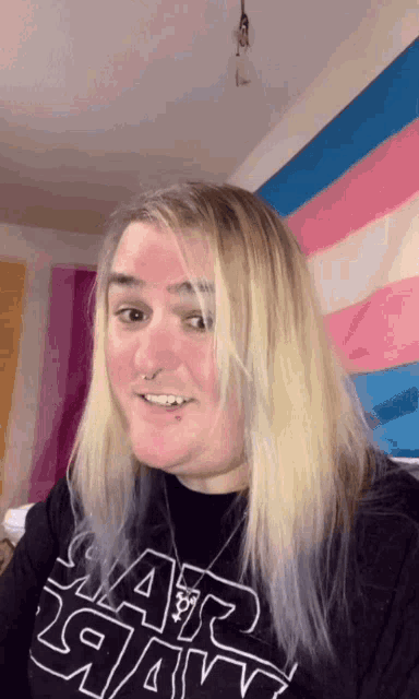a woman with long blonde hair is wearing a black star wars shirt .