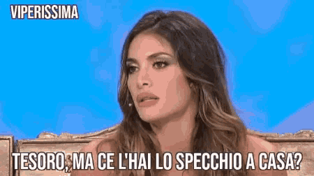 a woman sitting on a couch with the words tesoro ma ce l ' hai lo specchio a casa