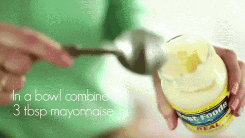 a person is pouring mayonnaise into a glass jar