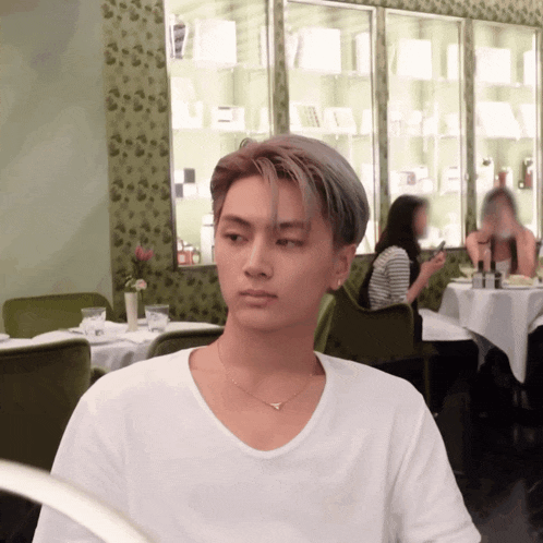 a man in a white t-shirt is sitting in a restaurant