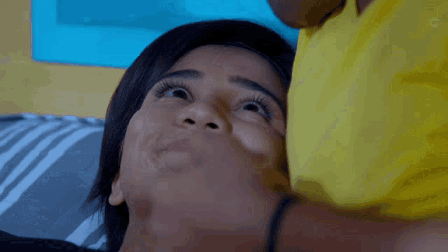 a close up of a woman 's face with a yellow shirt behind her
