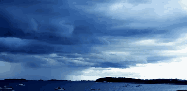 a stormy blue sky over a body of water with boats in it