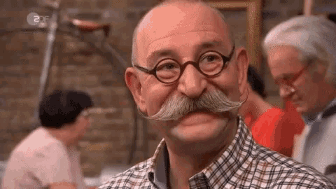 an older man with glasses and a mustache is smiling .