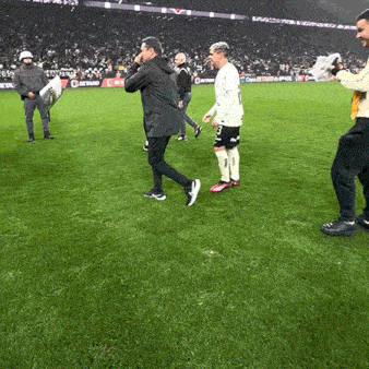 a group of men are standing on a soccer field with a man holding a pillow in his hand .