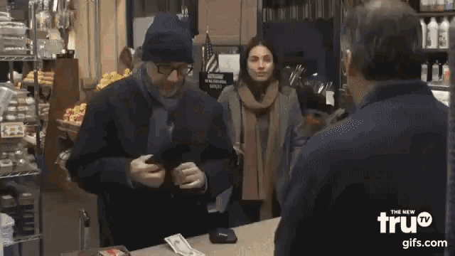 a man is using a scale in a grocery store while another man stands behind him .