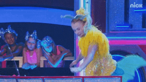 a girl in a yellow mermaid costume is standing in front of a sign that says nick