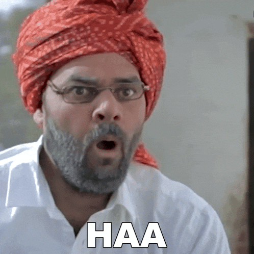 a man with a beard wearing glasses and a red turban has haa written on his shirt