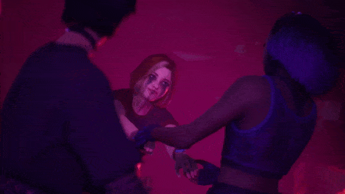 a group of people are dancing in a dark room with red lights