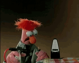 beaker from the muppet show is holding a stuffed animal in his hands
