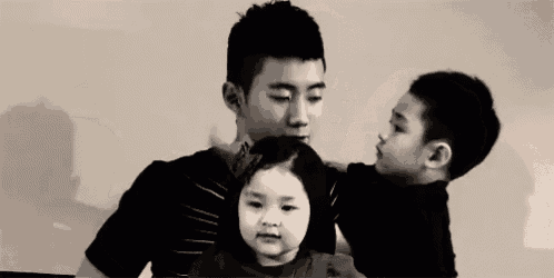 a man is holding a little girl and a little boy in his arms .