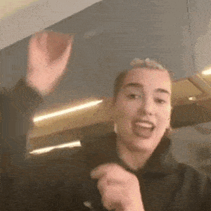 a woman is standing in a kitchen with her hands in the air and making a funny face .