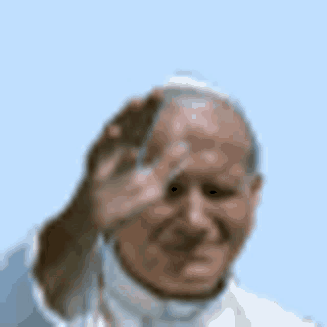 a man in a white robe is waving his hand in front of his face .