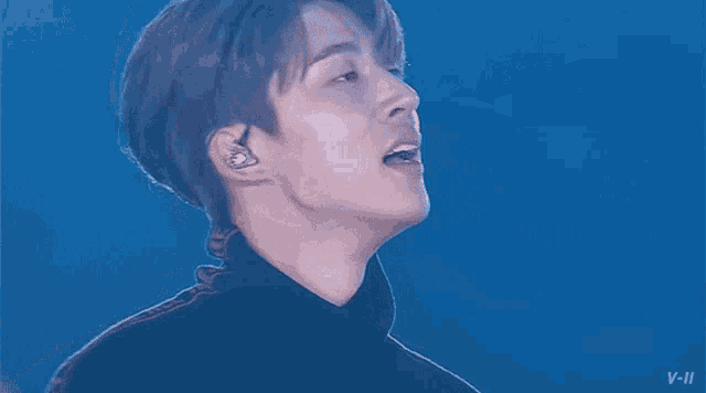 a close up of a person 's face with a blue background and a microphone .