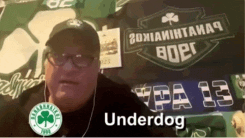 a man wearing a hat and earbuds is standing in front of a sign that says " underdog "