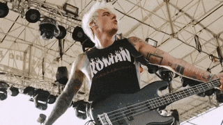 a man in a roman tank top is playing a bass guitar