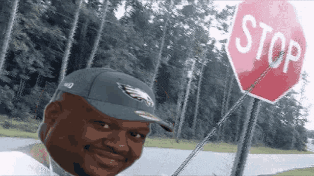 a man wearing a green eagles hat stands in front of a red stop sign