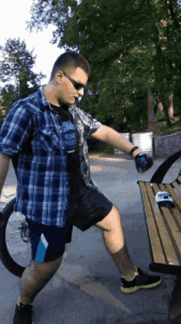a man in a blue plaid shirt is standing next to a bench