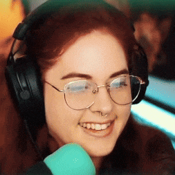 a woman wearing headphones and glasses is smiling in front of a blue microphone .