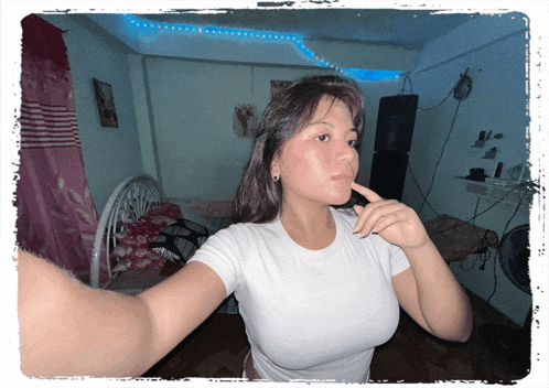a woman in a white shirt is taking a selfie in her bedroom