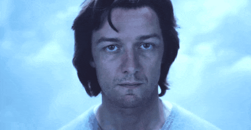 a close up of a man 's face with a blue sky behind him