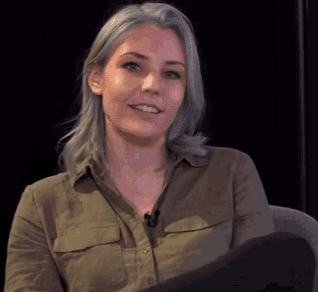 a woman with a microphone around her neck is smiling for the camera